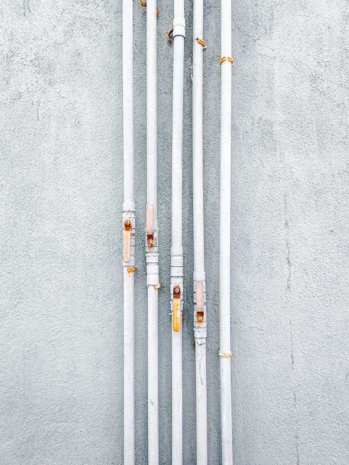 A minimalist view of industrial pipes aligned against a concrete wall in India, showcasing urban design.