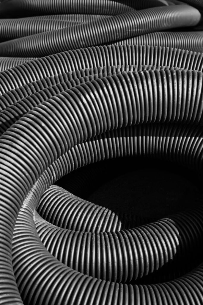 Black and white image highlighting the texture of coiled industrial corrugated tubes.
